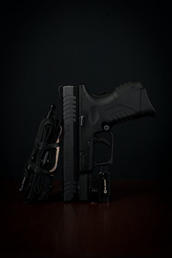 Detailed close-up of a handgun with tactical accessories against a dark backdrop.