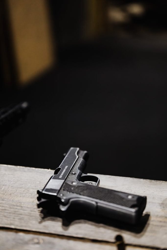 Detailed shot of a pistol placed on a wooden surface in an indoor setting.